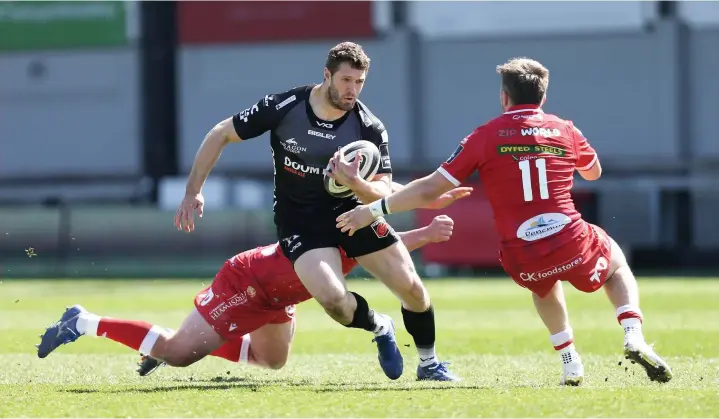  ?? Picture: Huw Evans Agency. ?? Dragons wing Jonah Holmes beats Steff Evans (No. 11) and Johnny Mcnicholl of the Scarlets as he races in to score a try at Rodney Parade on Sunday.