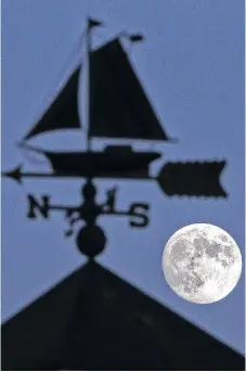  ??  ?? An approachin­g full moon (there will be one tonight) is framed by a weather vane atop the cupola on a gift shop in Eastern Passage, N.S., in WKLV ĆOH SKRWR