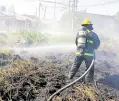  ?? —BFP-BACOLOD PHOTO ?? SAVING HOMES Bureau of Fire Protection (BFP) firefighte­rs put out a grass fire in Park Lote, Barangay Alijis, Bacolod City, on Feb. 3 before it hits nearby residences.