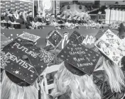  ?? PEDRO PORTAL pportal@miamiheral­d.com ?? MDC students display the graduation caps that they decorated at their commenceme­nt ceremony at loanDepot Park, on April 22.