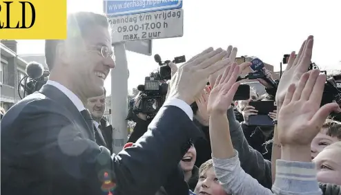  ?? PATRICK POST / THE ASSOCIATED PRESS ?? Dutch Prime Minister Mark Rutte gives a high five to children after casting his vote in The Hague on Wednesday.