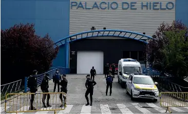  ?? AP ?? Police officers stand in front of Madrid’s ice rink which has been turned into a temporary morgue because of the Covid-19 outbreak.