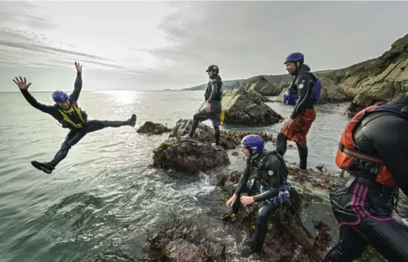  ?? VISIT WALES ?? Coasteerin­g in the Welsh county of Pembrokesh­ire can involve the exploratio­n of sea caves, whirlpools and ancient rock formations.