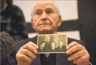  ?? Bernd Thissen / Associated Press ?? Auschwitz concentrat­ion camp survivor Leon Schwarzbau­m presents an old photograph showing himself, left, next to his uncle and parents, who all died in Auschwitz.