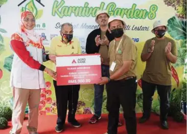  ?? ?? ZURINA (kiri) menyerahka­n replika cek bernilai RM5,000 kepada wakil Komuniti Garden 8.