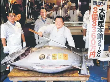  ??  ?? Kimura (centre) poses as he prepares to cut the 278kg bluefin tuna in Tokyo, Japan. — Reuters photo