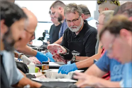  ?? TIM COOK/THE DAY ?? Participan­ts in a barbecue school run by four-time national barbecue champion Myron Mixon learn how to prepare a host of barbecue favorites at Myron Mixon Smokers in Waterford.