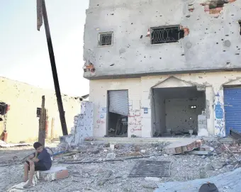  ??  ?? A child sits in front of a damaged building hit by the forces loyal to putschist Gen. Khalifa Haftar in Tripoli, June 27, 2020.