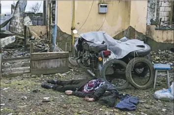  ?? Ronaldo Schemidt AFP/Getty Images ?? THE KILLINGS of Ukrainian civilians during Russian occupation were concentrat­ed in the more densely populated areas but also occurred in outlying hamlets. Above, a body in Bucha, a suburb of Kyiv, in April.