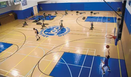  ?? ADOLPHE PIERRE-LOUIS/JOURNAL ?? Players practice basketball on the court at the Jewish Community Center gym while observing COVID-19 social distancing practices Wednesday. Half the gym floor has been outfitted with exercise equipment.