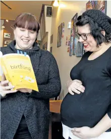  ?? CLIFFORD SKARSTEDT/EXAMINER ?? Jennifer Avis, left, and Steph Hayes of Hello Baby!, who offer prenatal and postnatal care, look at the pages of a book on birthing during the launch of the business at Black Honey restaurant on Wednesday.