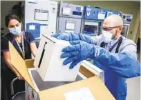  ?? MICHAEL CIAGLO GETTY IMAGES ?? Terrence Wong opens a shipment of the Pfizer-BioNTech COVID-19 vaccine at a VA medical center in Aurora, Colo.