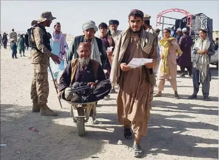  ??  ?? MIEDO. Un soldado afgano observa cómo sus compatriot­as huyen a través del cruce de Chaman, en la frontera con Pakistán.