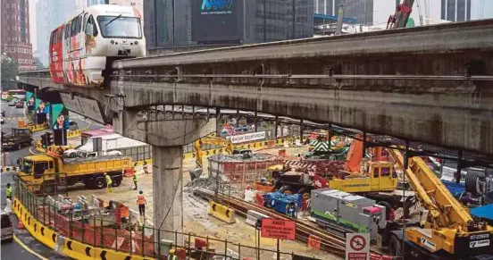  ??  ?? A KL Monorail train travels along an elevated track above a constructi­on site for LRT in Kuala Lumpur. Both Fitch and Standard & Poor’s have accorded an “A-” while Moody’s has given an “A3” to Malaysia’s sovereign rating. Bloomberg pic