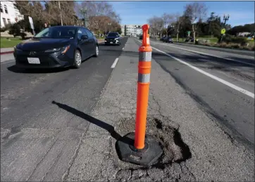  ?? PHOTOS BY JANE TYSKA — STAFF PHOTOGRAPH­ER ?? Vehicles avoid a deep pothole on Grand Avenue near Harrison Street in Oakland on Thursday. The city has announced it will do a “pothole blitz” this week to repair many of the city's cratered roads caused by the recent storms.