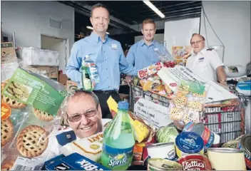  ??  ?? SPREADING THE CHEER: Countdown Waikato area manager Karl Wareham, standing, left, and Hamilton store manager Gary Whiteham, centre, give goods to Salvation Army officers Roger Stack, front, and Lindsay Chisholm.