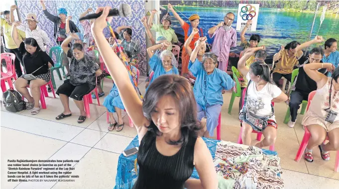  ??  ?? Panita Rujikietka­mjorn demonstrat­es how patients can use rubber band chains to exercise as part of the ‘Stretch Rainbow Forward’ regiment at the Lop Buri Cancer Hospital. A light workout using the rubber bands can be lots of fun as it takes the...