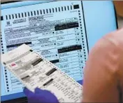  ?? Matt York Associated Press ?? AN ELECTION worker verifies a ballot Nov. 10 at the Maricopa County recorder’s office in Phoenix.