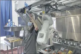  ?? MISO ROBOTICS ?? A technician makes an adjustment to a robot at Miso Robotics’ White Castle test kitchen in Pasadena on Thursday.