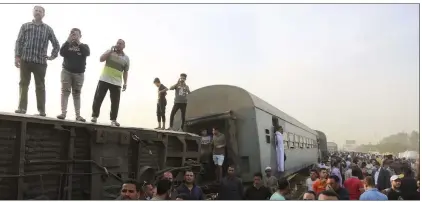  ?? Fadel Dawood The Associated Press ?? People gather Sunday at the site where a passenger train derailed, injuring at least 100 people, in Banha, Qalyubia province, Egypt.