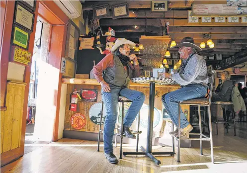  ?? GABRIELA CAMPOS/THE NEW MEXICAN ?? From left, locals Samuel Montoya and Randy Rodriguez catch up at Cowgirl BBQ on April 9. ‘Business has been fantastic,’ co-owner Patrick Lambert says.