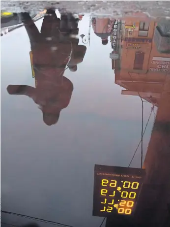  ??  ?? CRUMBLING: People walk past a currency exchange display reflected in a puddle in St Petersburg last month. Russia’s financial system is now weak, but there was a time when it boomed.