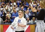  ?? ?? Marcelle Scheyer (right), wife of Duke coach Jon Scheyer, applauds after presenting a basketball signed by coach Scheyer to Samantha DiMartino as an honoree of the Scheyer Family Kid Captain Program, during a timeout in Wednesday’s game between Duke and Louisville.