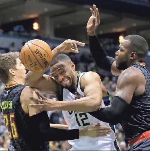  ?? Aaron Gash / The Associated Press ?? Milwaukee’s Jabari Parker (12) loses control of the ball between Atlanta’s Kyle Korver (left) and Paul Millsap during the first half of Friday’s game in Milwaukee. The Hawks won 114-110.