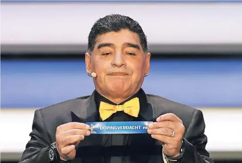  ?? FOTO: IMAGO, MONTAGE FERL ?? Diego Maradona bei der WM-Auslosung im Dezember 2017. Das fiktive Los „Dopingverd­acht“hat unsere Redaktion ihm in die Hände gelegt.