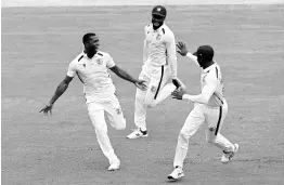  ?? PHOTO BY DARREN ENGLAND ?? West Indies’ Shamar Joseph (left) celebrates with teammates after taking the wicket of Australia’s Cameron Green on the second day of their Test match in Adelaide, Australia, on January 18.