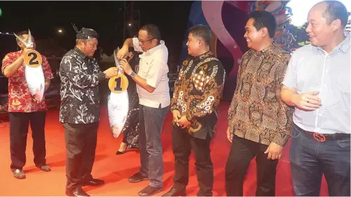  ?? BOY SLAMET/JAWA POS ?? PENAWAR TINGGI: Bupati Saiful Ilah menyerahka­n bandeng kawak dengan berat 7,76 kg kepada Boy Arifin, perwakilan dari Kahuripan Nirwana Village, di alun-alun pada Rabu malam (13/11).