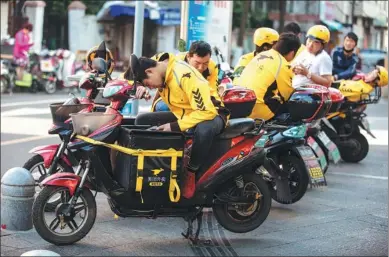  ?? JIA DONGLIU / FOR CHINA DAILY ?? Food delivery drivers wait for orders on a street in Ningbo, Zhejiang province.