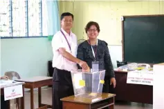  ??  ?? Wong Ling Biu (left) accompanie­d by his wife slots his ballot paper into the ballot box.