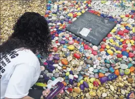  ?? Kayla O’brien ?? The Associated Press Lizbeth Davila looks over the rocks painted with inspiratio­nal messages Monday at the “Hugs Not Hate” heart memorial outside the Pulse nightclub in Orlando, Fla.