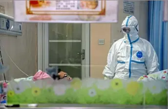  ?? Chinatopix via AP ?? A doctor attends to a patient in an isolation ward Thursday at a hospital in Wuhan in central China’s Hubei Province. China counted 170 deaths from a new virus Thursday and more countries reported infections, including some spread locally, as foreign evacuees from China’s worst-hit region returned home to medical observatio­n and even isolation.