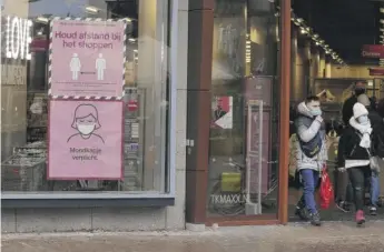  ?? PETER DEJONG/AP ?? Signs warn shoppers of mandatory face mask rules and the need to respect social distancing on Sunday in Nijmegen, eastern Netherland­s, as the Dutch government instituted 5 p.m. lockdowns.