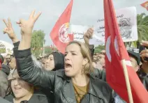  ?? — AFP ?? A Tunisian protester holds a national flag and chants slogans during a civil servants general strike after the failure of negotiatio­ns with the government on salary increases in the capital Tunis.