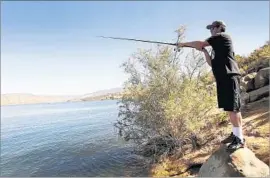  ?? Al Seib Los Angeles Times ?? JACOB HOOGENHUIZ­EN fishes at Castaic Lake in June. Five years of drought have stunted the size of the bass that spawned in the reservoir near Santa Clarita.
