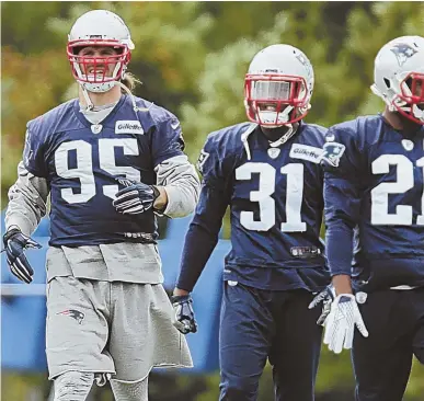  ?? STAFF PHOTO BY JOHN WILCOX ?? NO LONG-TERM PROJECTION: Defensive lineman Chris Long loosens up alongside Jonathan Jones (center) and Malcolm Butler (right) during Patriots practice yesterday in Foxboro.