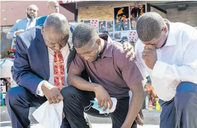  ?? STEPHEN MATUREN/GETTY ?? Quincy Mason Floyd, center, son of George Floyd, and attorney Ben Crump, left, kneel Wednesday at the site where Floyd was killed.