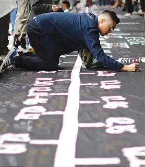  ??  ?? A participan­t writes a message on a memorial timeline banner during an anti-government rally at Edinburgh Place in Hong Kong.