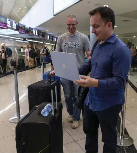  ?? Antonie Robertson / The National ?? Slovakian Robert Koval, right, checks his emails while waiting to check in with his business associate Jan Gloncak. Passengers at Abu Dhabi Internatio­nal Airport say they are relieved the laptop ban has been lifted