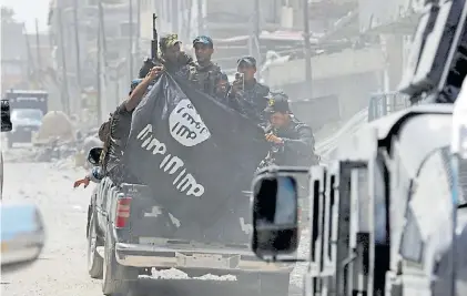  ?? RTRS ?? Conquista. Fuerzas de seguridad iraquíes con una bandera del ISIS que arrebataro­n a la banda en fuga.