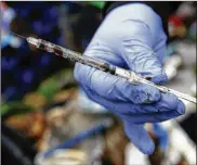  ?? AP ?? Steph Gaspar, a volunteer with The Hand Up Project, an addiction and homeless advocacy group, holds a used needle used for drug injection found while cleaning up a homeless encampment in Everett, Wash.