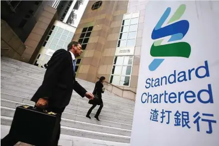  ??  ?? People walk outside the main branch of Standard Chartered in Hong Kong. The banking group’s ability to facilitate trade between emerging economies and developed countries came under threat on Monday when New York State’s top banking regulator, the...