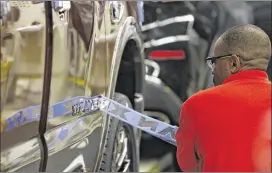  ?? ROGELIO V. SOLIS / ASSOCIATED PRESS ?? A technician applies a logo stencil on a Titan truck at the Nissan Canton Vehicle Assembly Plant in Canton, Miss., in April. The Federal Reserve released its “Beige Book” survey of economic conditions Wednesday.