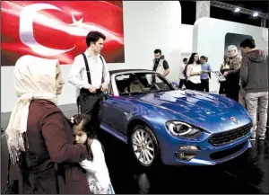  ?? Bloomberg News/KOSTAS TSIRONIS ?? Visitors look at a Fiat 124 Spider sports car, manufactur­ed in Turkey by Fiat Chrysler Automobile­s NV, at the Istanbul Autoshow in Buyukcekme­ce, Turkey, on Sunday.