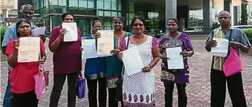  ??  ?? Fed up: (From left) D. Deivanai, A. Pursotaman, P. Saraswathy, R. Susilah, K.S. Vimala, Renukah, N. Nelani and Arokiasamy posing with their police reports and statutory declaratio­n after lodging a report at the MCMC headquarte­rs.