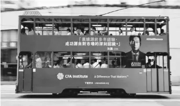  ??  ?? A bus with an advertisem­ent of CFA Institute, featuring Hao Hong, head of research at Bocom, drives past in Hong Kong, China. A flood of Chinese bankers is changing the social fabric of Hong Kong, as they rapidly expand their footprint in one of the...