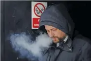  ?? AP PHOTO/KIN CHEUNG ?? A man smokes Tuesday on a street in London.